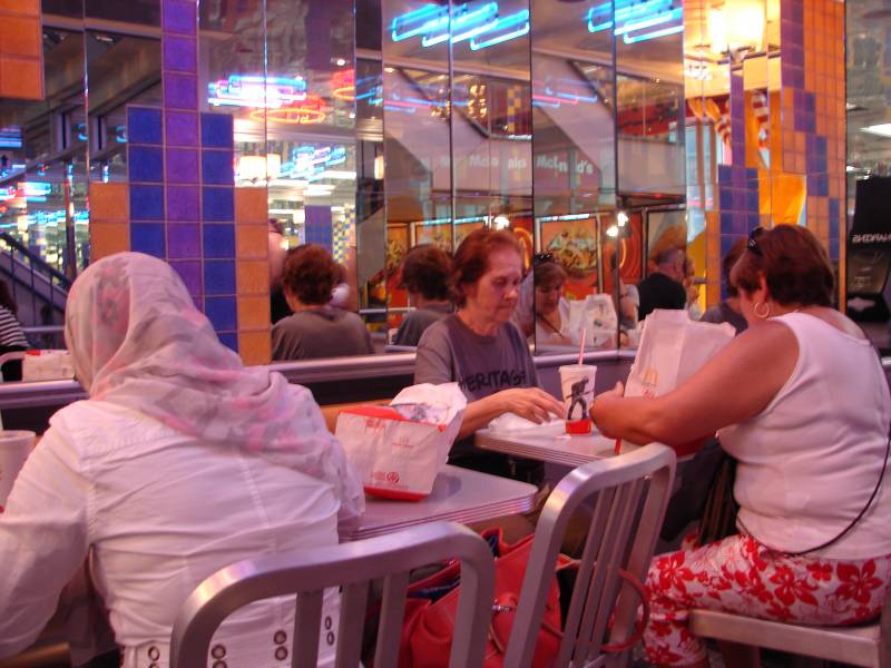Tres mujeres comen hamburguesas en un restaurante de comida rápida.