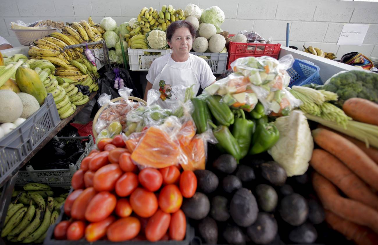 Una mujer compra frutas y verduras el 6 de septiembre de 2014, en un mercado de San Salvador. / Efe