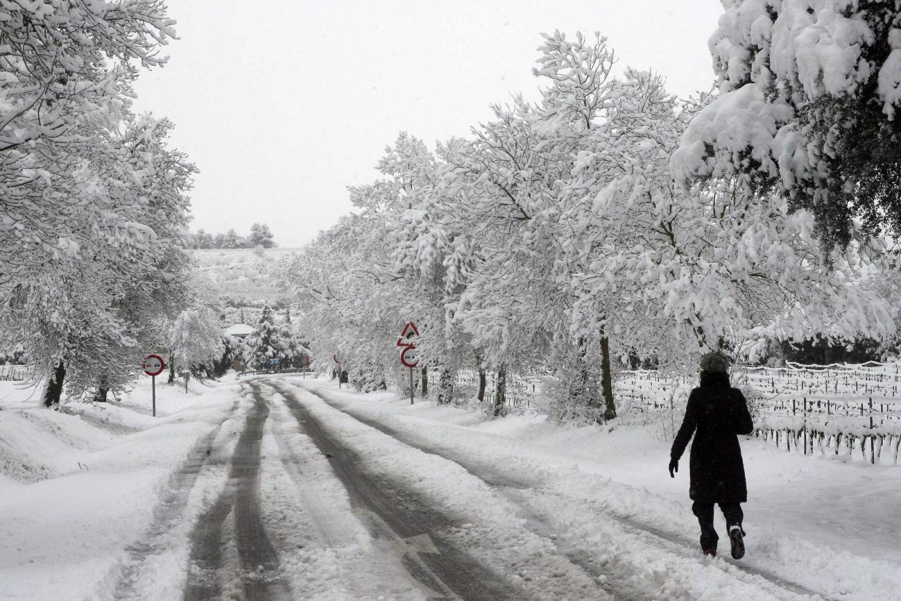 Una mujer camina por una carretera nevada en las inmediaciones de l’Espluga de Francoli (Tarragona), uno de los pueblos catalanes afectados por el temporal de nieve. / EFE