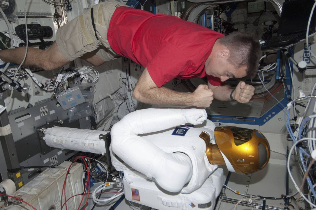 El astronauta estadounidense Chris Cassidy bromea con el robot del laboratorio Destiny en la Estación Espacial Internacional tras una sesión de operaciones realizadas por el Robonaut 2. / NASA