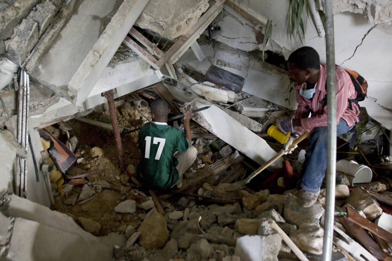 Dos haitianos tratan de despejar los escombros en un intento de rescatar a los supervivientes en el Hotel Montana de Puerto Príncipe.