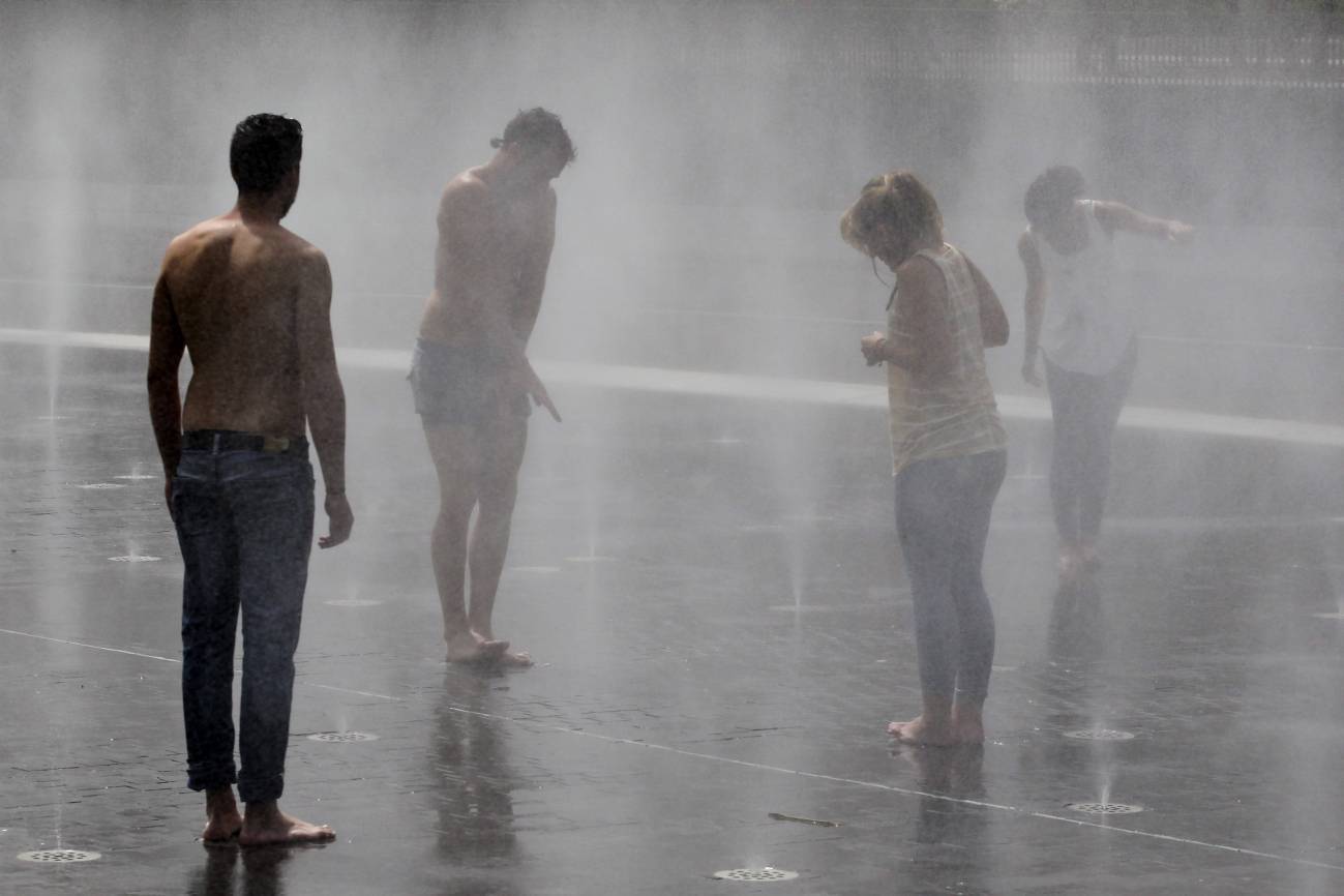 Varias personas se refrescan en una fuente de Madrid Río debido a las altas temperaturas del verano de 2015. / EFE/Javier Lizón