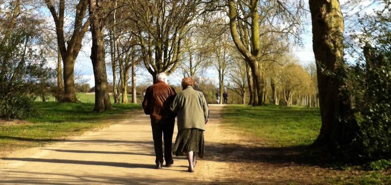 Dos personas mayores caminan por un espacio natural