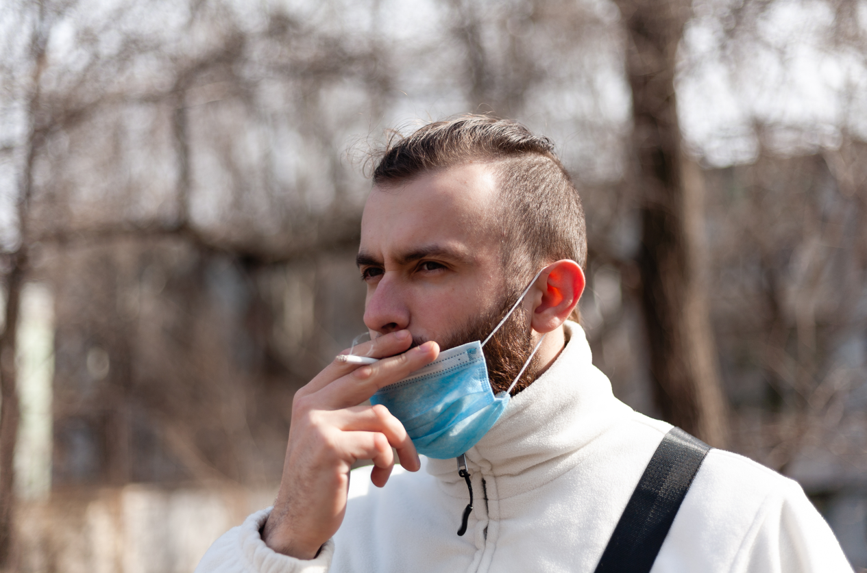 hombre fumando en la calle con mascarilla