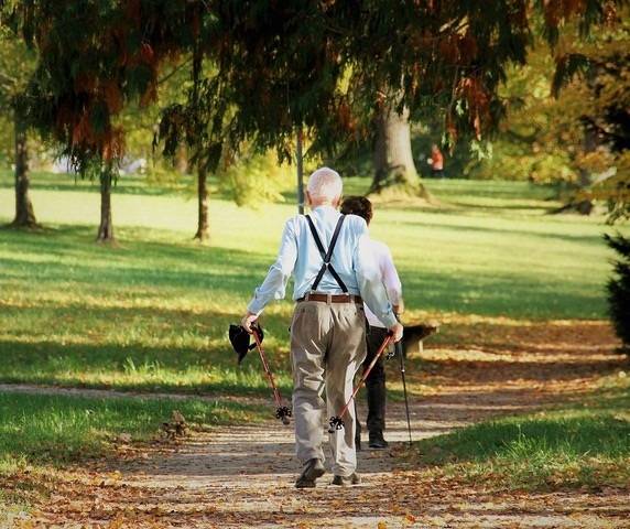 Fotografía de dos personas de avanzada edad paseando por un parque.
