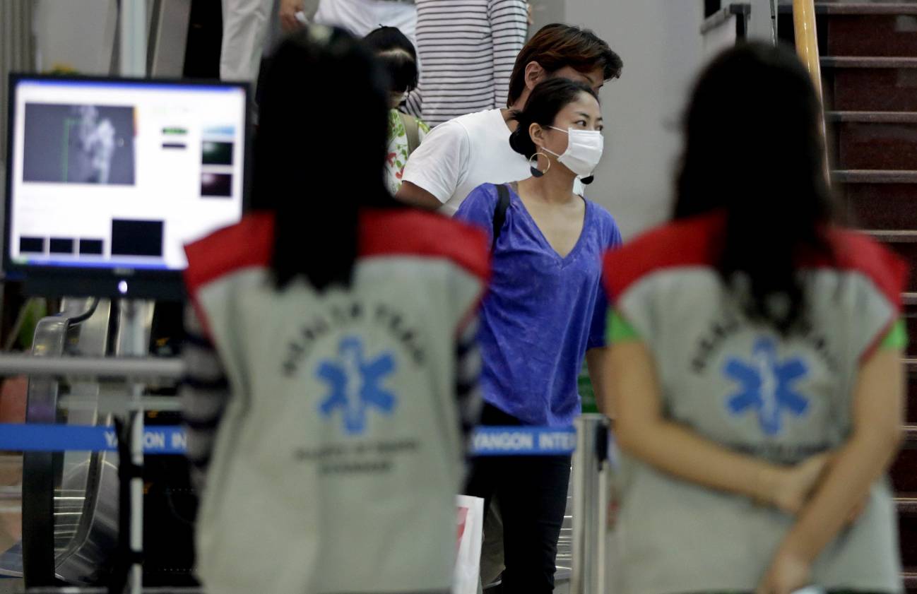 Miembros de un equipo sanitario observan la temperatura corporal de los viajeros en el aeropuerto de Rangún (Birmania). EFE / Archivo