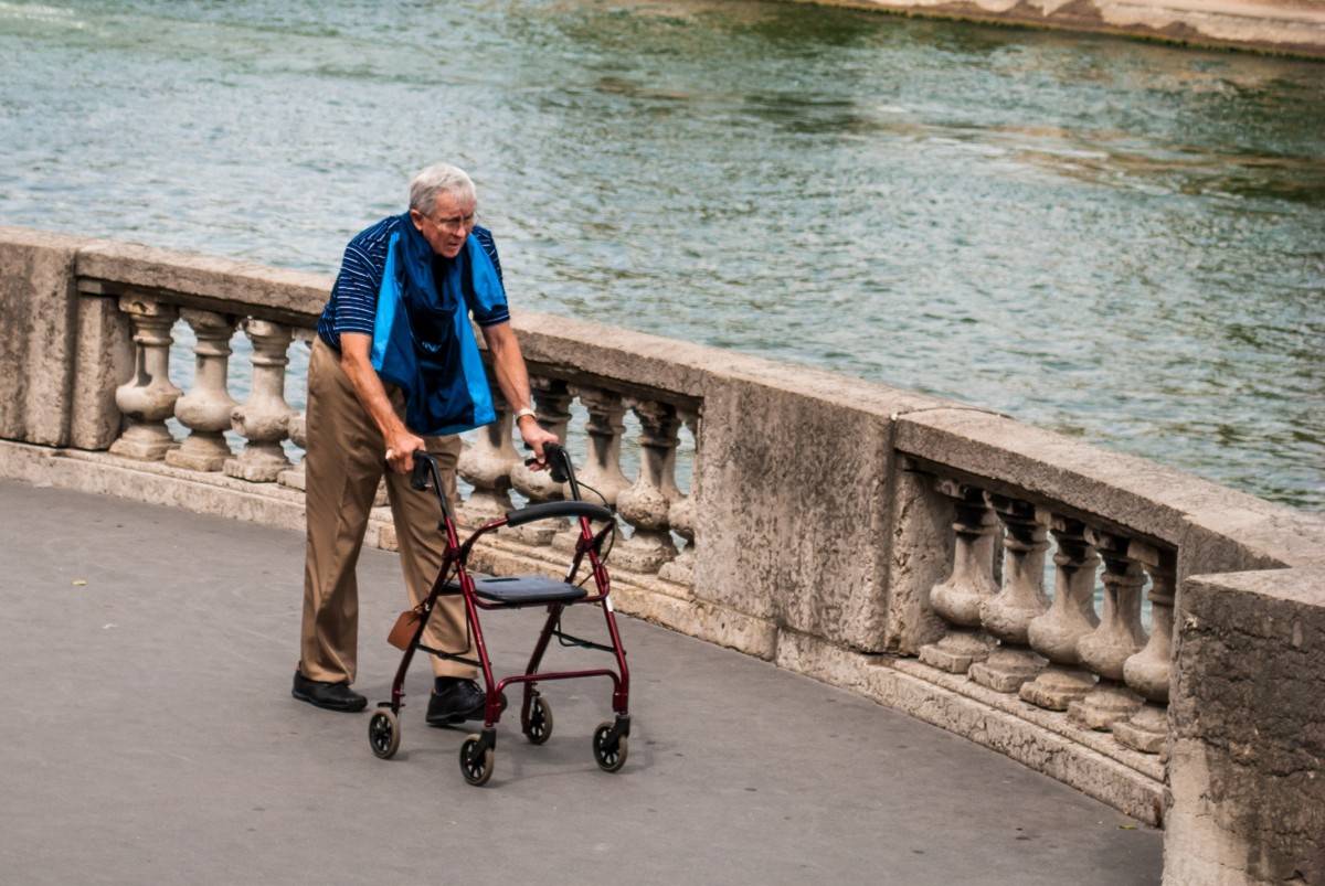 Un hombre camina con una ayuda junto al río Sena