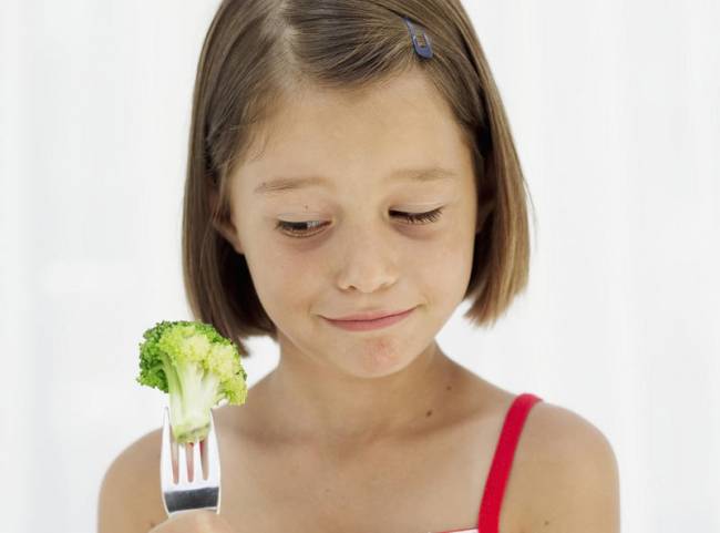 a girl is eating broccoli
