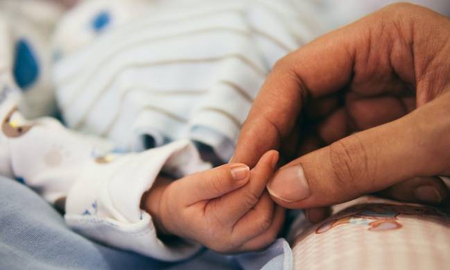 Una madre acaricia la mano de su bebé