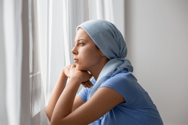 mujer con cáncer mirando por la ventana
