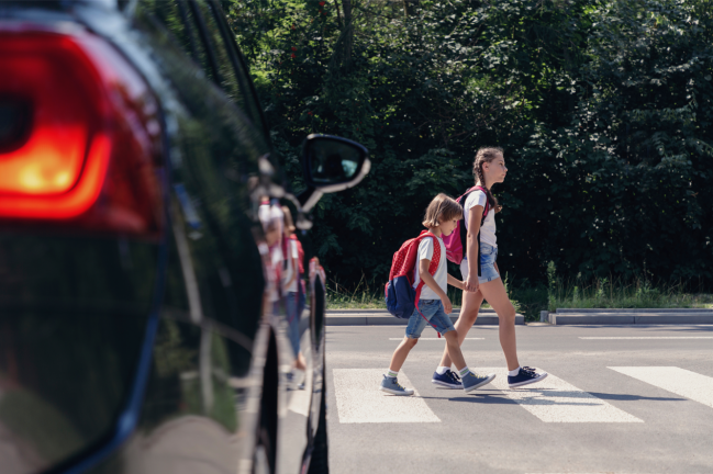 niños cruzando una calle con tráfico