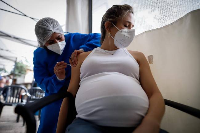 Personal médico aplica una dosis de la vacuna Moderna a una mujer embarazada