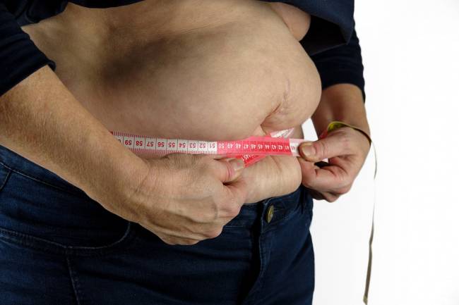 Mujer con sobrepeso midiéndose la cintura
